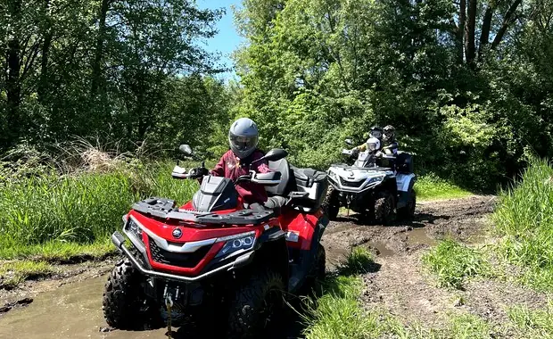 Czerwony quad podczas przejazdu jasną leśną trasą
